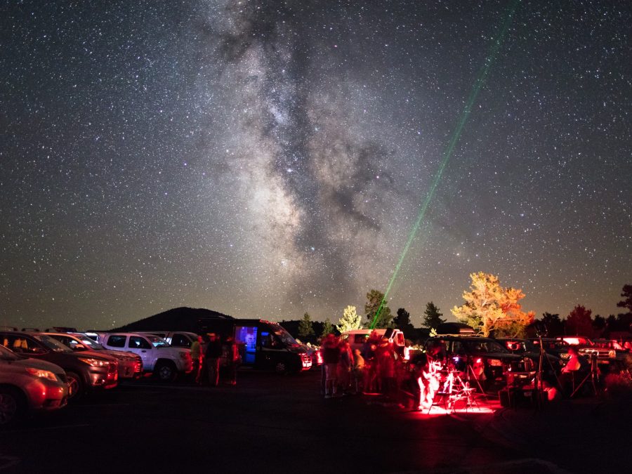 A park ranger points a green laser at the Milky Way for a crowd at a guided star party
