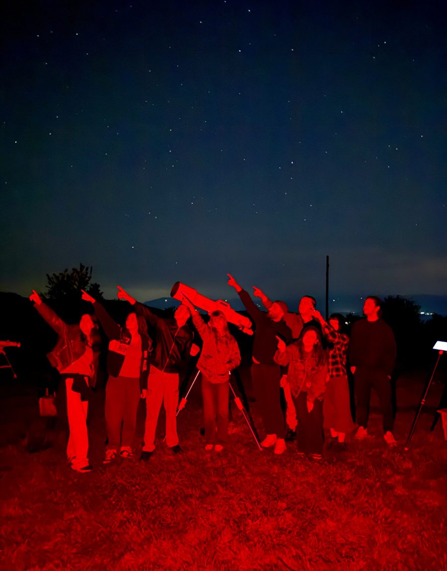 A group silhouetted in red light looking up at a star-filled night sky