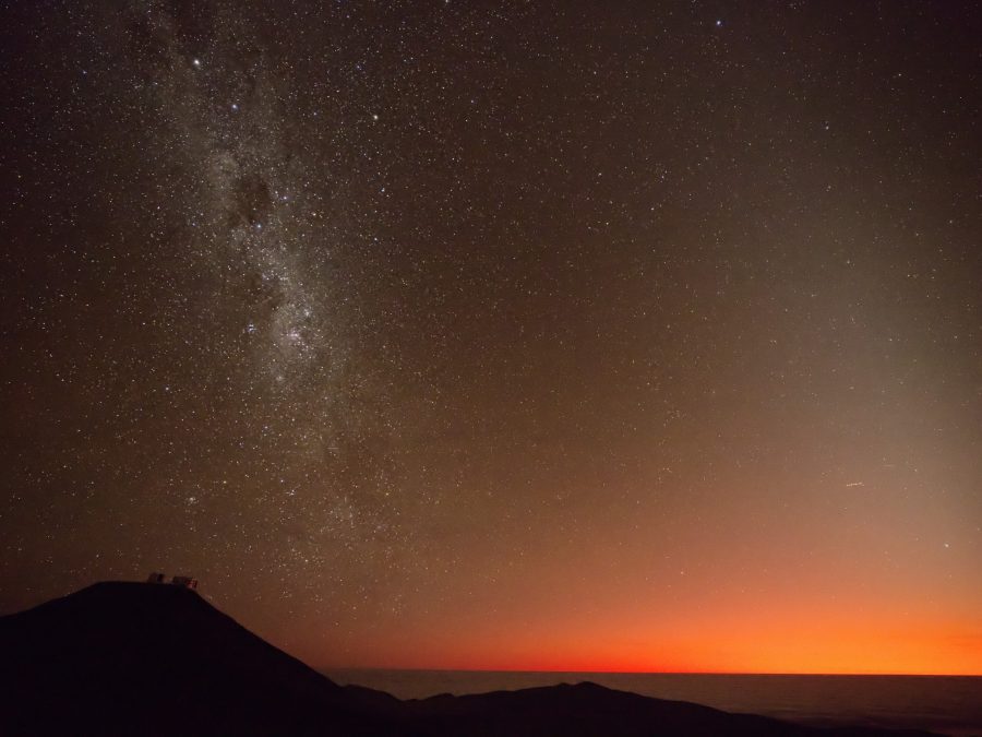 A dramatic fiery twilight sky with the Milky Way already visible over an observatory ridge
