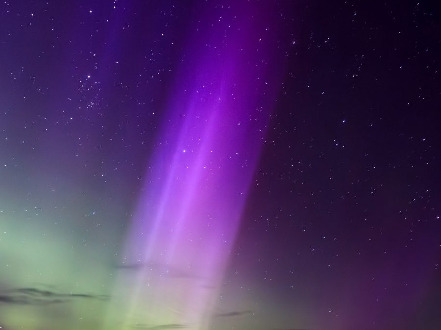 A multicolored aurora borealis pillar glowing over a dark horizon