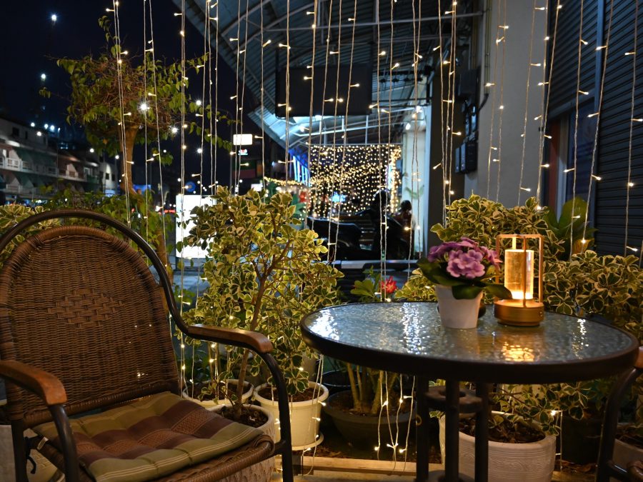 A lantern-lit outdoor seating corner strung with warm string lights at night