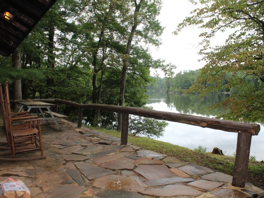 A covered wooden porch and deck overlooking a calm lake