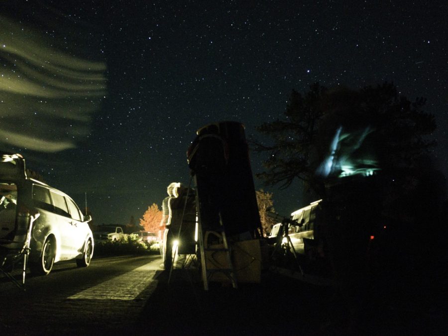 People with a telescope observing the Milky Way at a night star party
