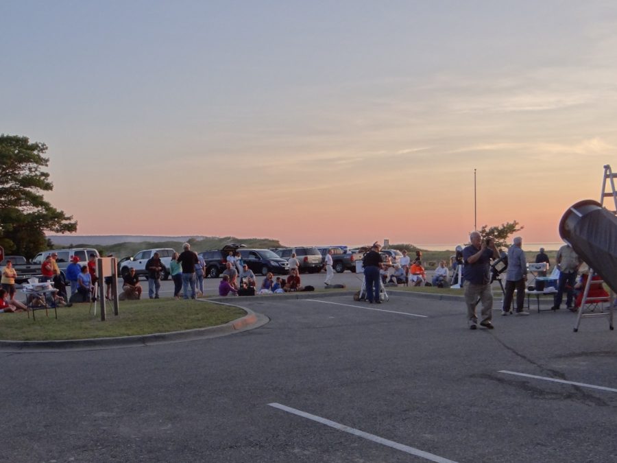 People and telescopes silhouetted against a colorful twilight sky