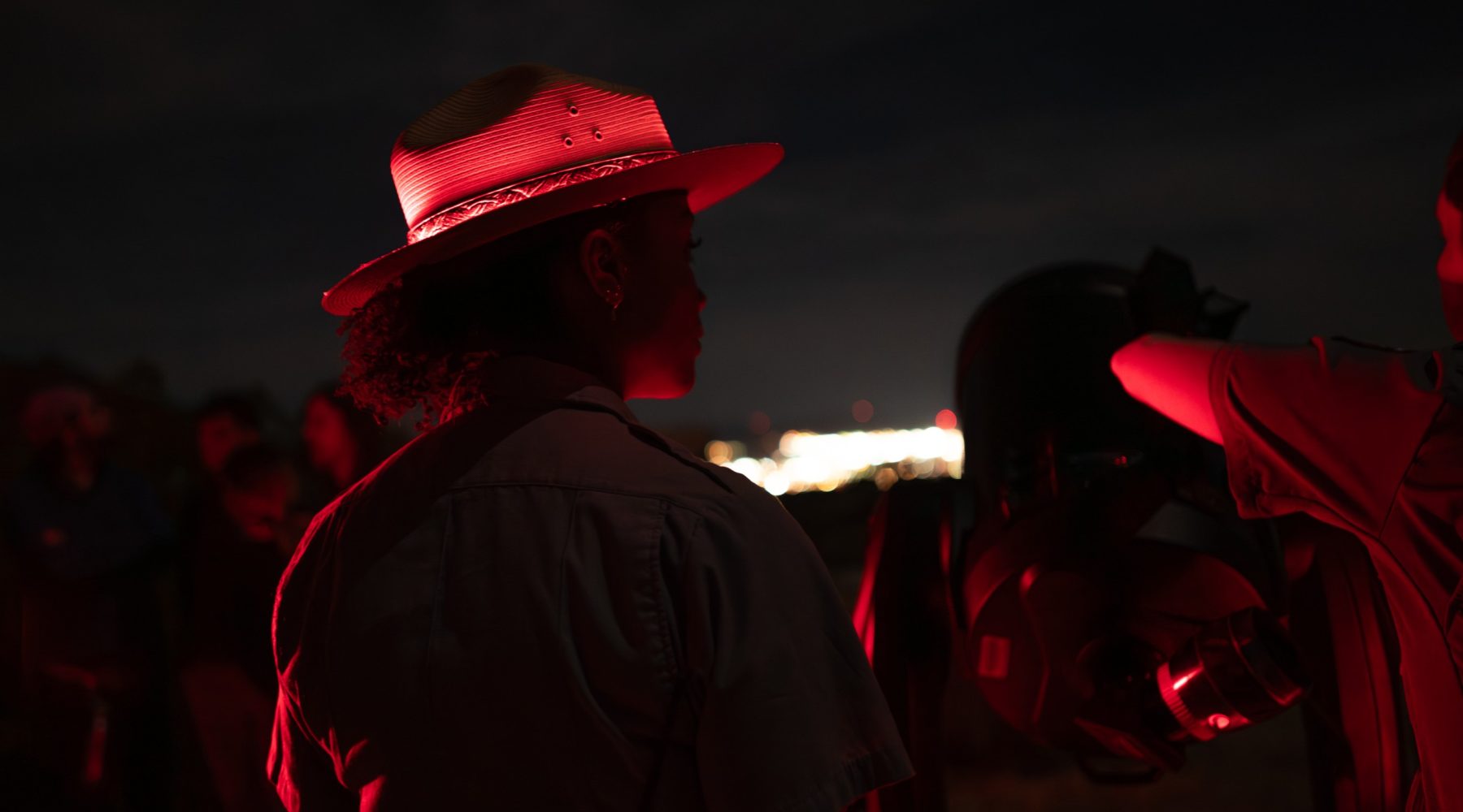 A park ranger illuminated by red light at a night astronomy program