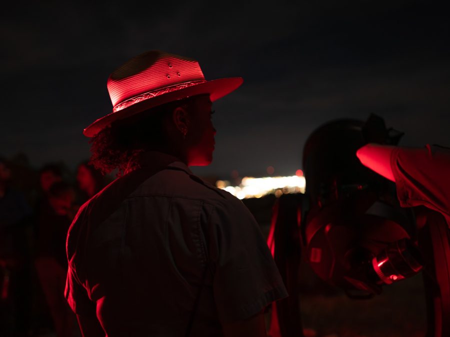 A park ranger illuminated by red light at a night astronomy program