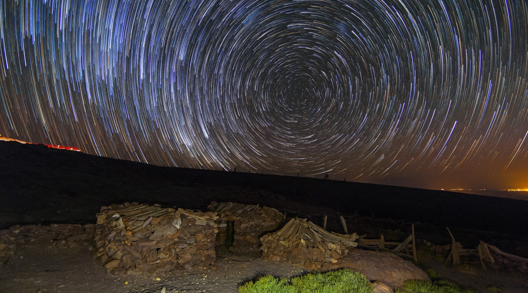Star trails over stone ruins at night, long exposure