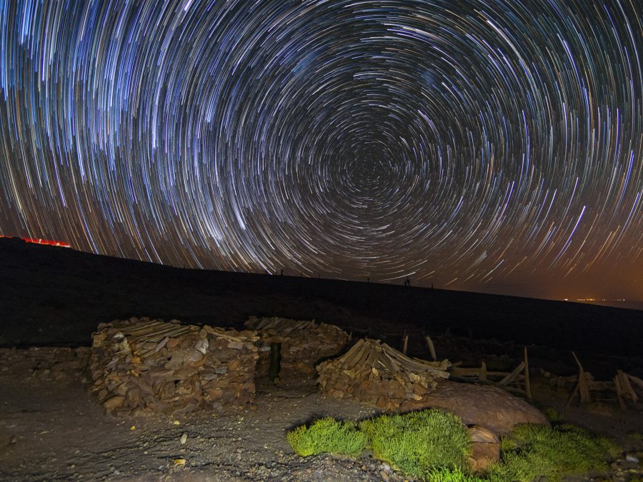 Star trails over stone ruins at night, long exposure